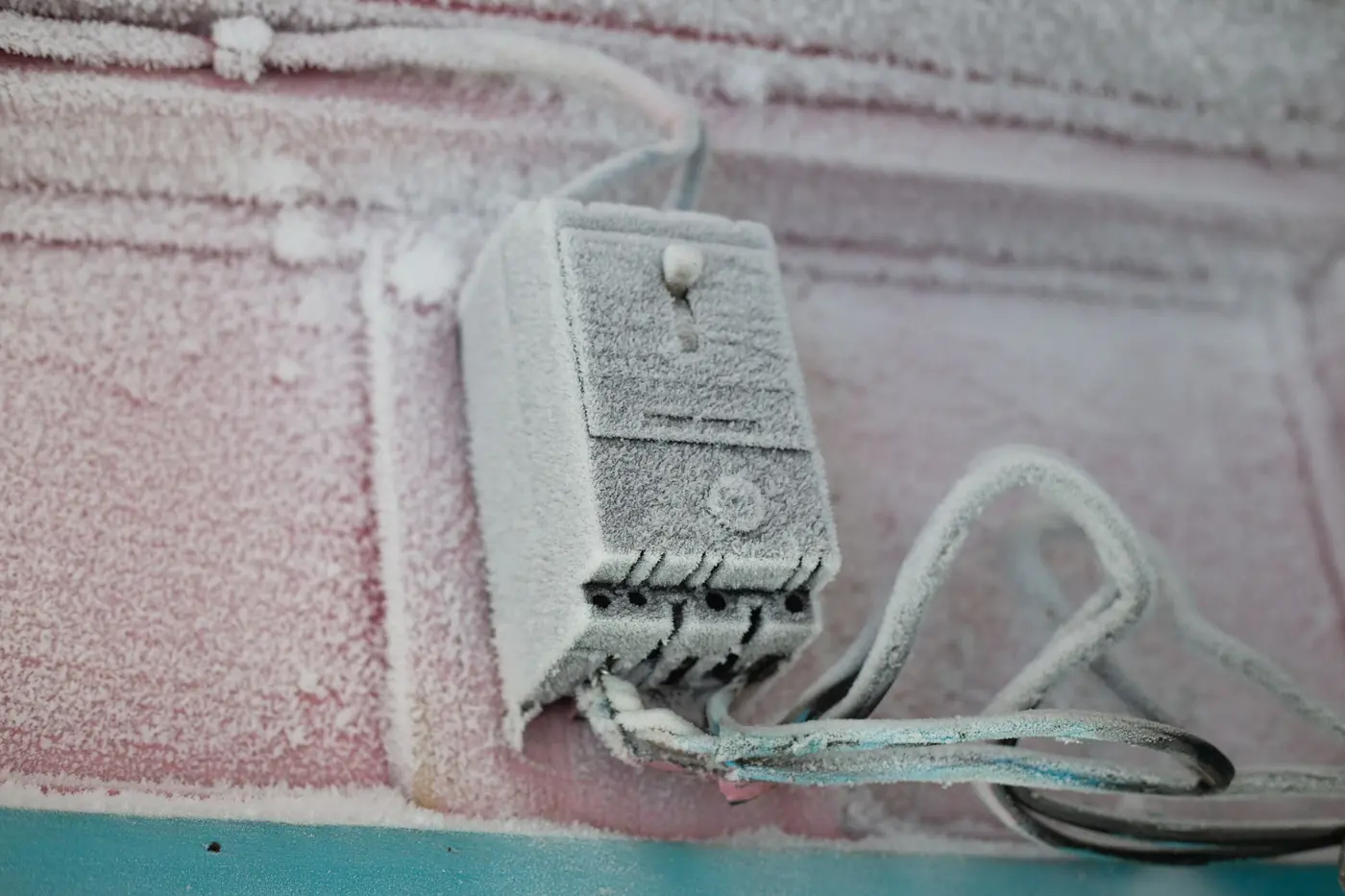 An electrical enclosure on an outside wall, covered in frost.